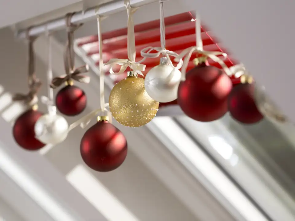 Christmas ornaments hanging near a VELUX roof window, festive and bright.