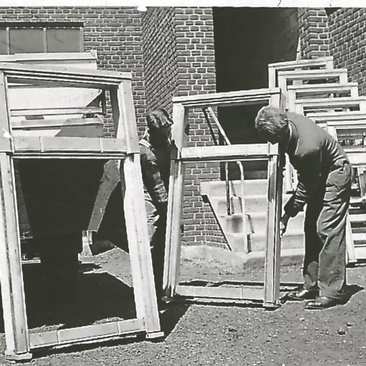 Altes Foto von Arbeitern, die Fenster auf einer Baustelle einbauen.