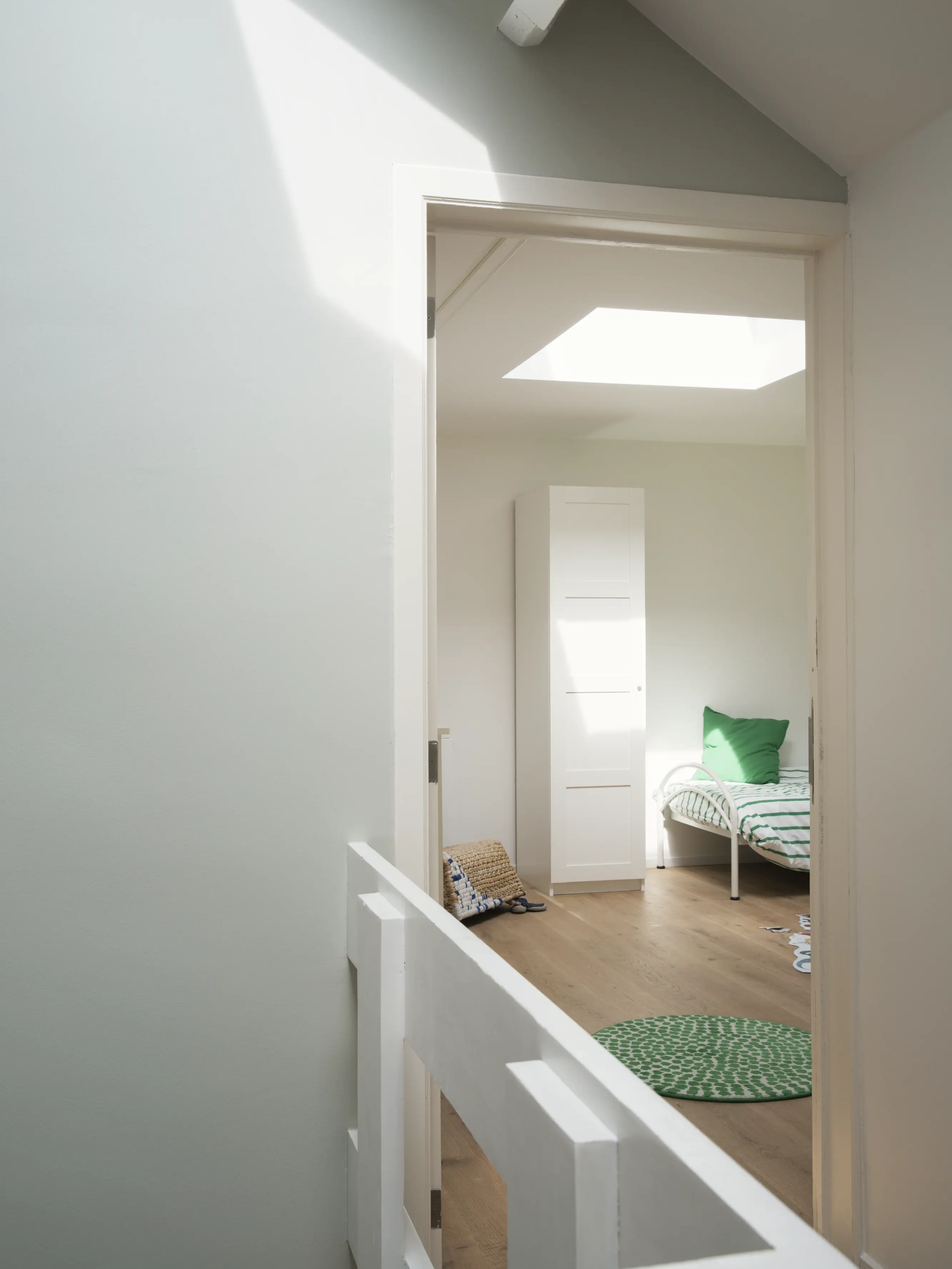 Attic bedroom with sloped ceiling and VELUX roof window, natural light entering.