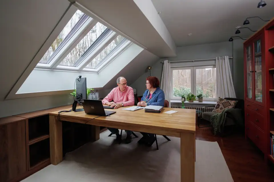 Couple sous une fenêtre de toit 3en1 VELUX dans un bureau sous combles rénové