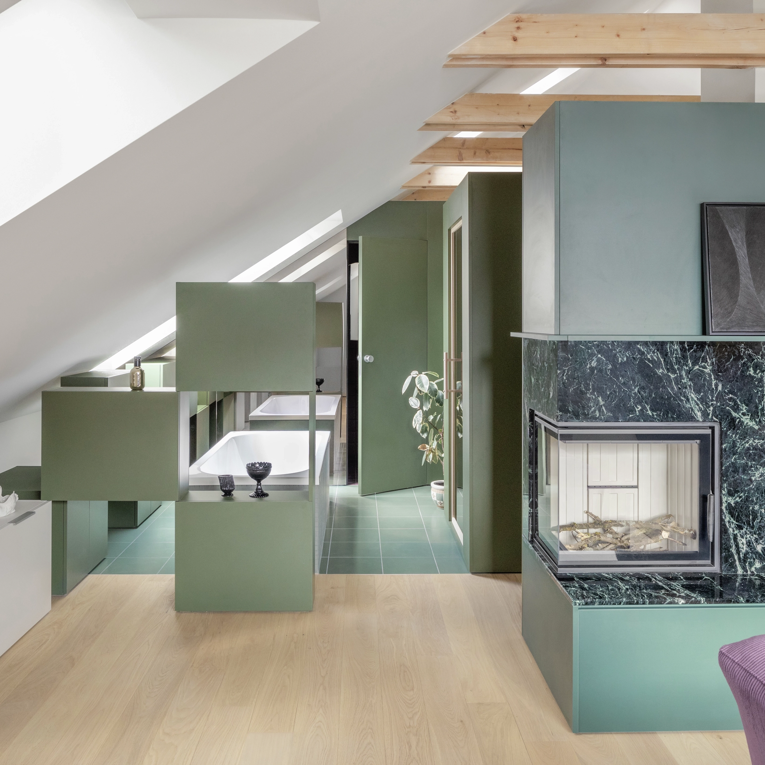 Combles en open space avec meuble modulaire qui divise la zone jour d'une zone avec baignoire.