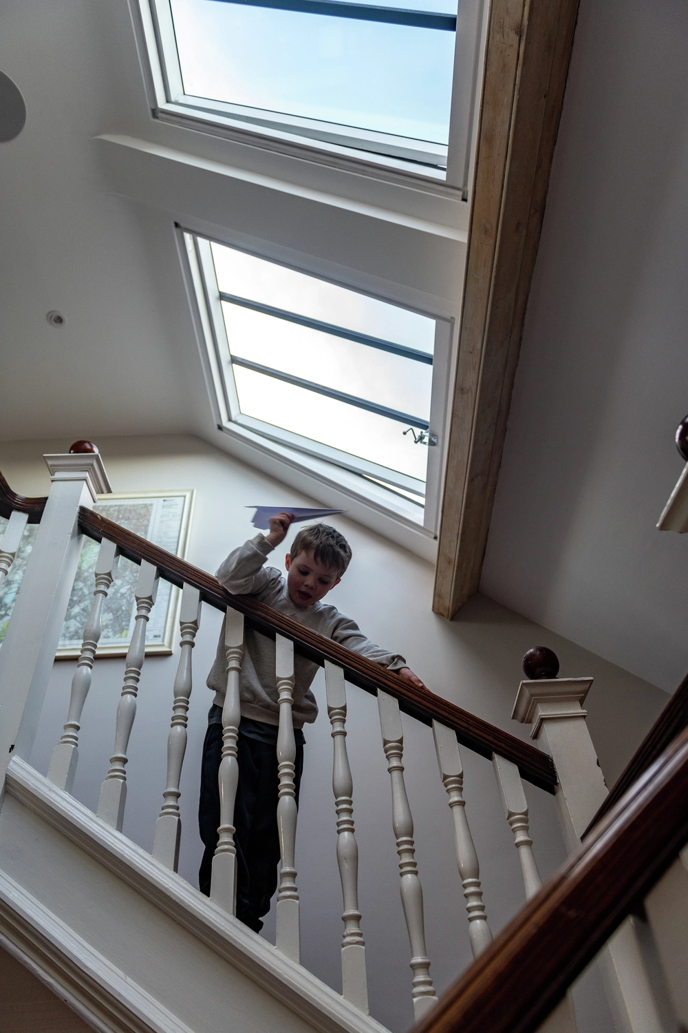 kid playing with paperplain on staircase under a velux roof window