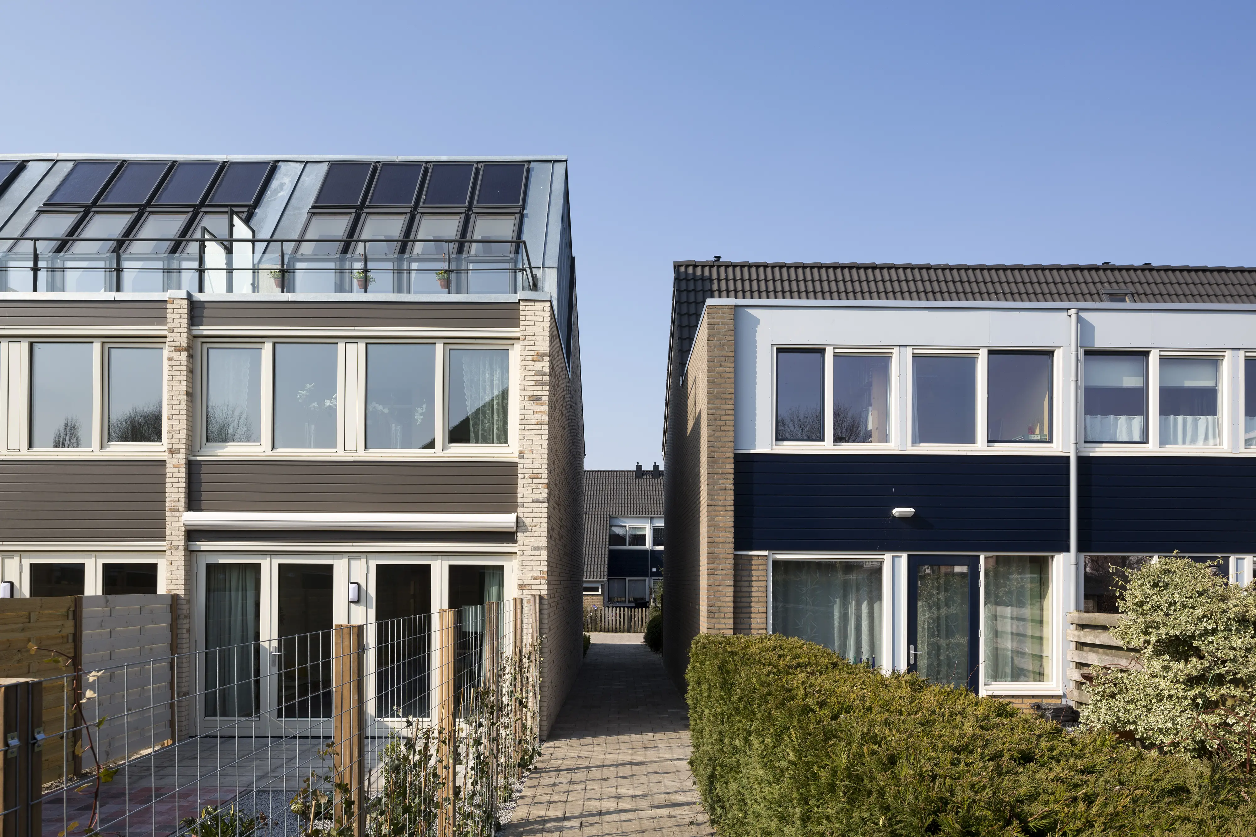 Two terraced houses, one with solar panels, showcasing modern and traditional designs.