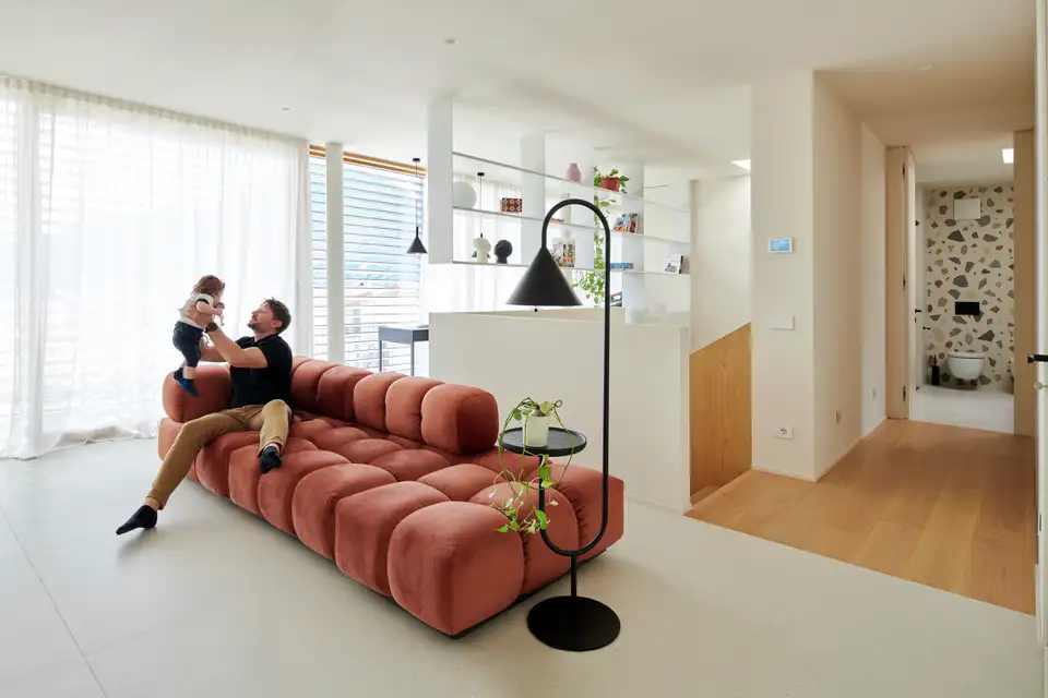"Een man speelt met zijn kind op de zetel in een woonkamer vol licht en sfeer."