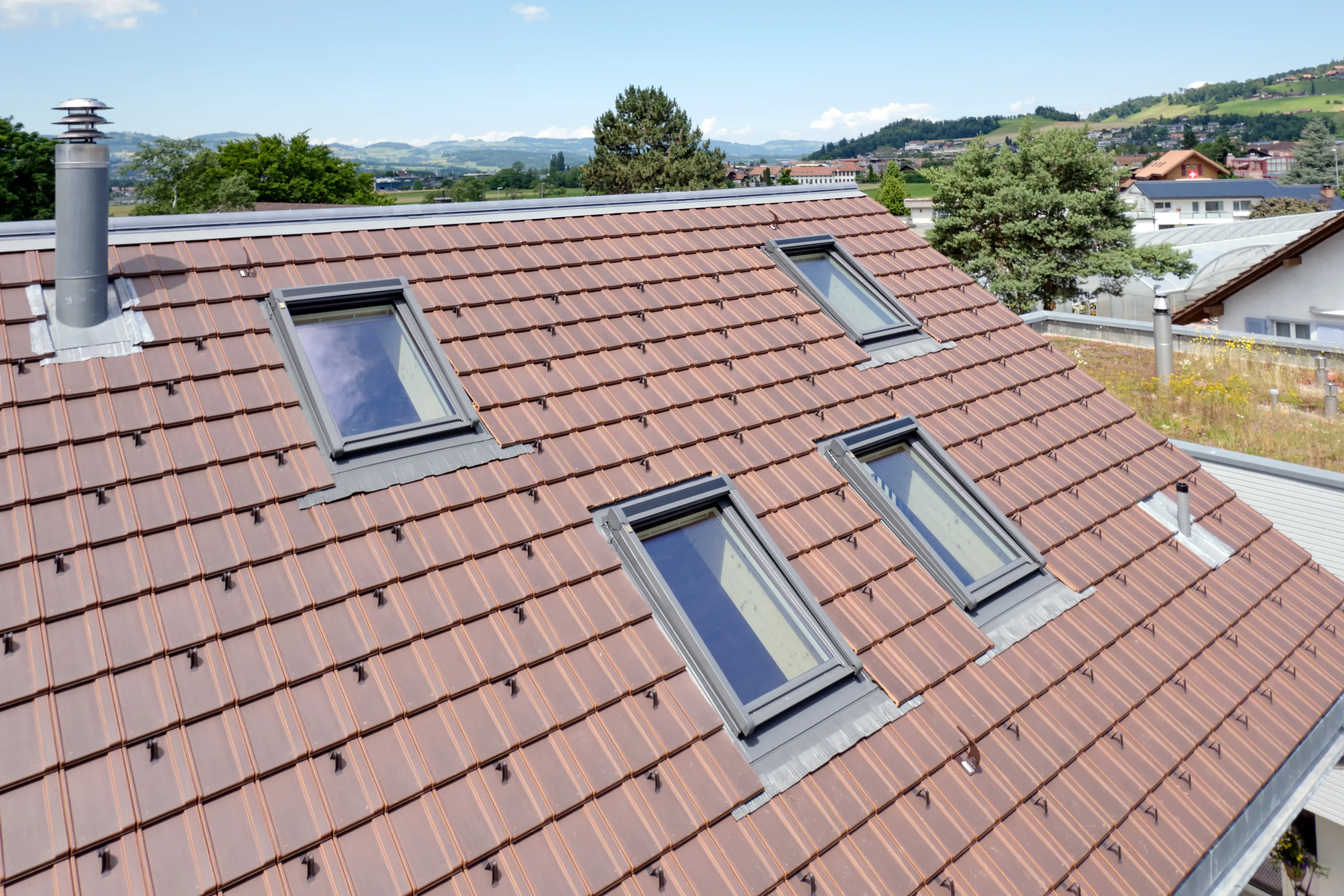 Steep pitched roof with red tiles and VELUX roof windows.