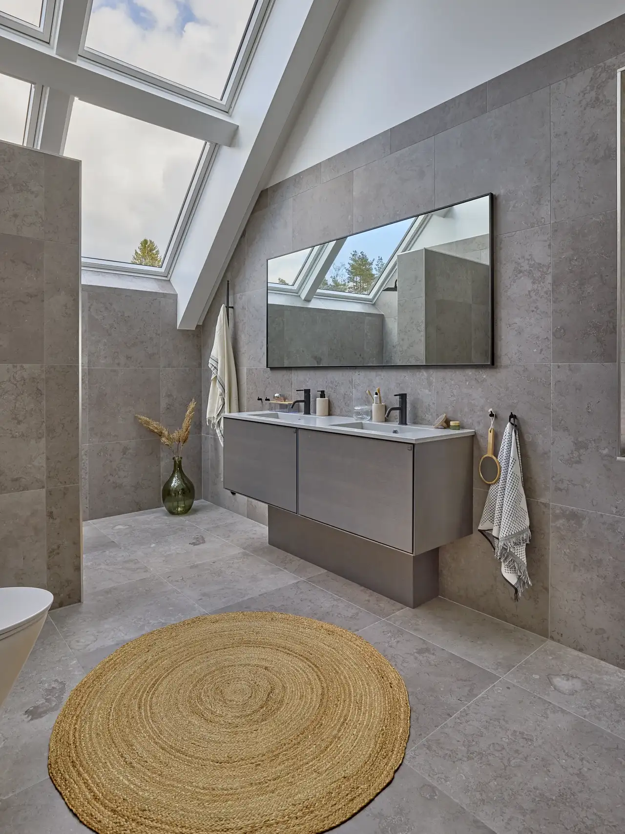 Salle de bain avec plafond incliné et grandes fenêtres de toit VELUX, au design moderne.