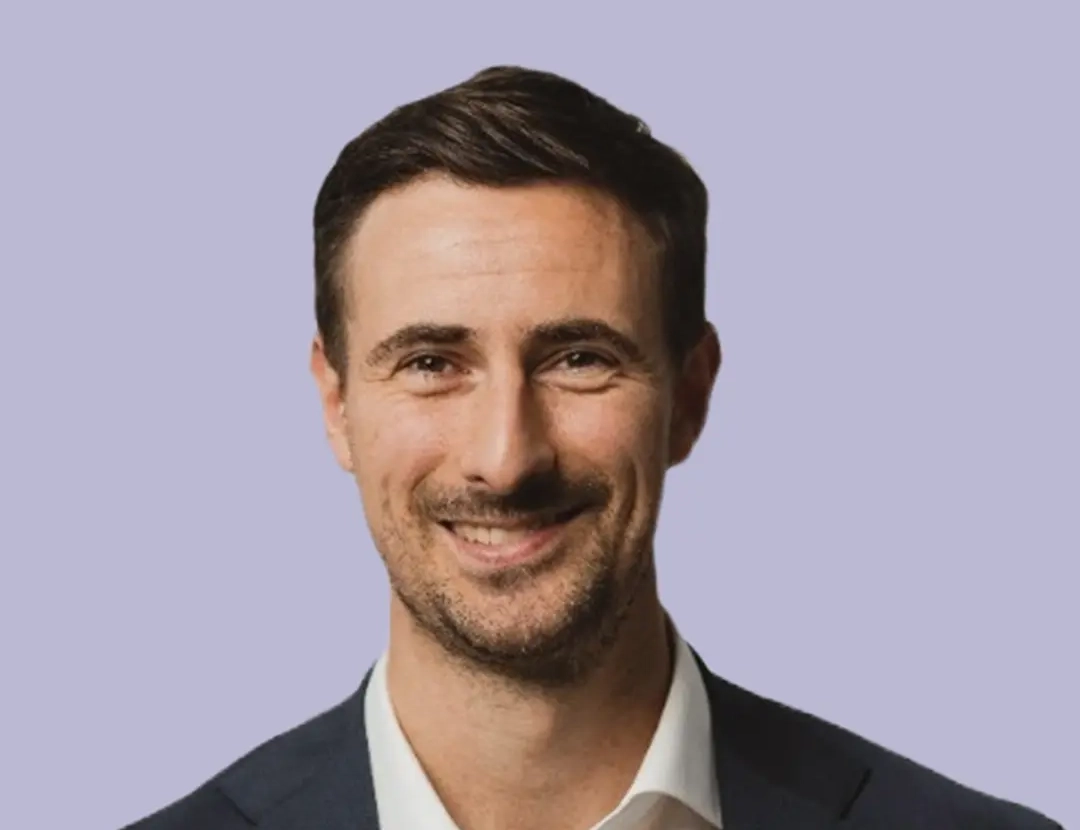 Person in a dark blazer and white shirt, professional attire.