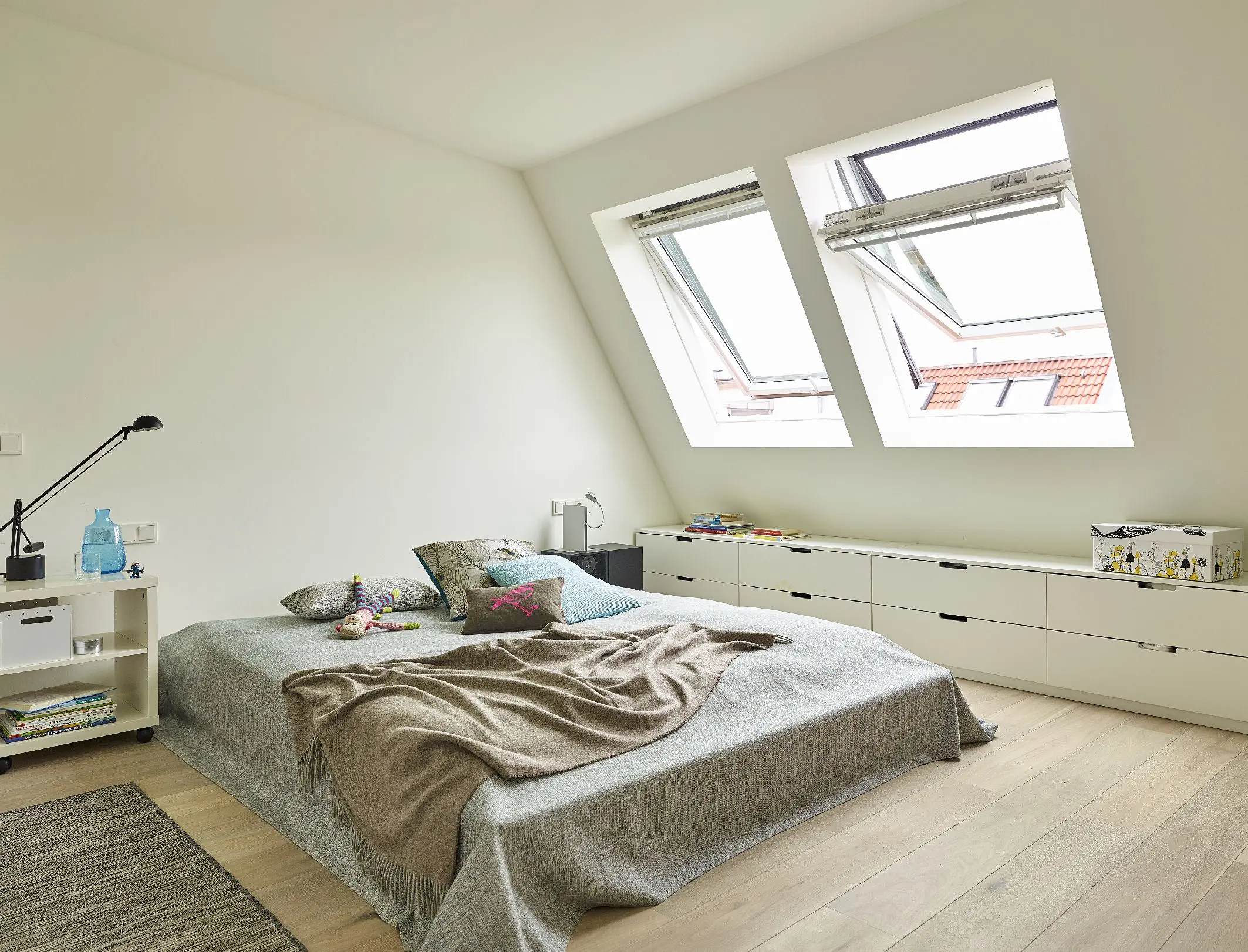 Spalnica v nežnih pastelih z odprtim strešnim oknom VELUX.