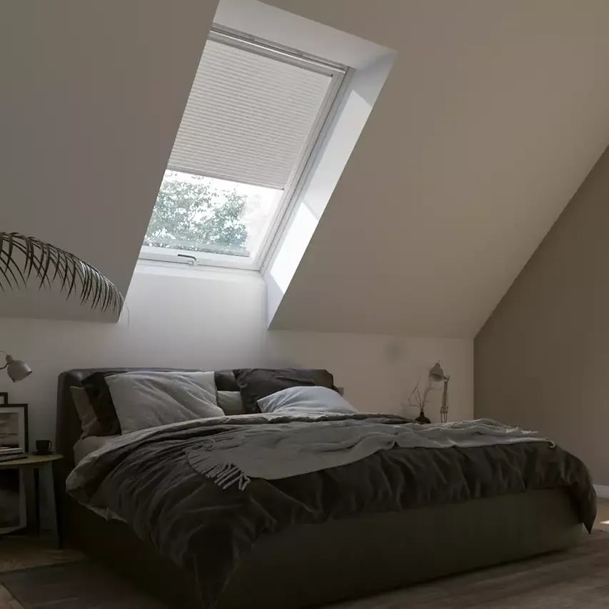 Attic bedroom with sloped ceiling and VELUX roof window, natural light entering.