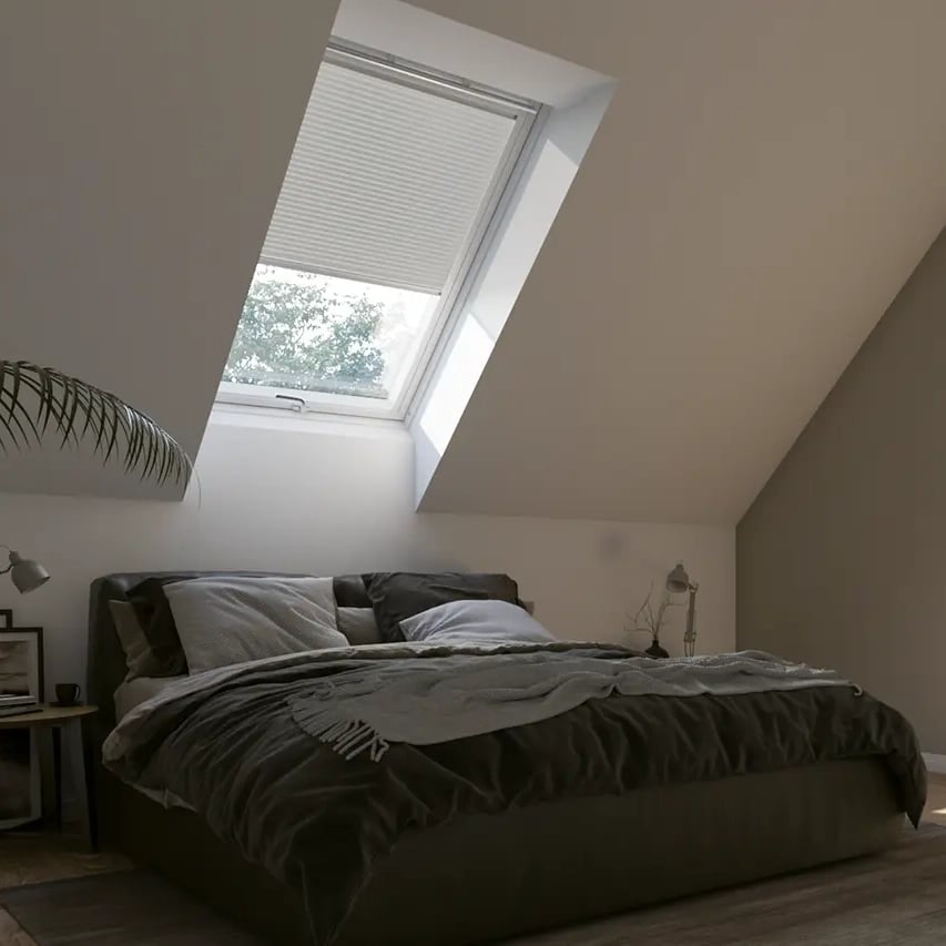 Attic bedroom with sloped ceiling and VELUX roof window, natural light entering.