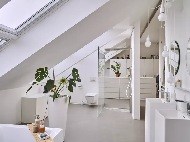 Modernes Badezimmer mit weißen Einrichtungen und einem VELUX Dachflächenfenster, das für natürliches Licht sorgt.