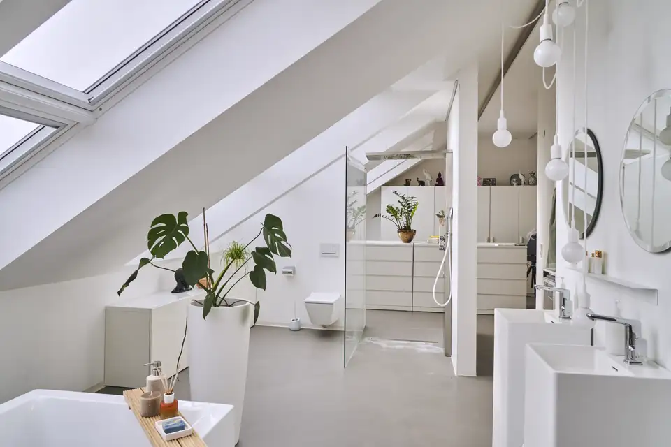 Mansarda con bagno e cabina armadio in mansarda con finestre per tetti VELUX e armadi e mobili bianchi.