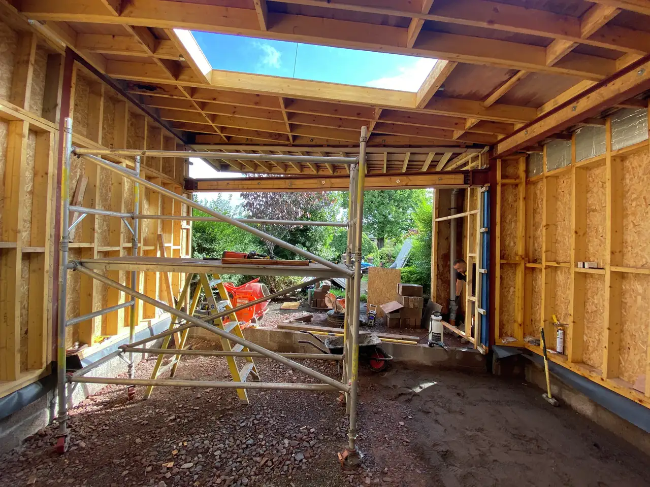 Timber home extension under construction with two VELUX flat roof windows and open garden view. 