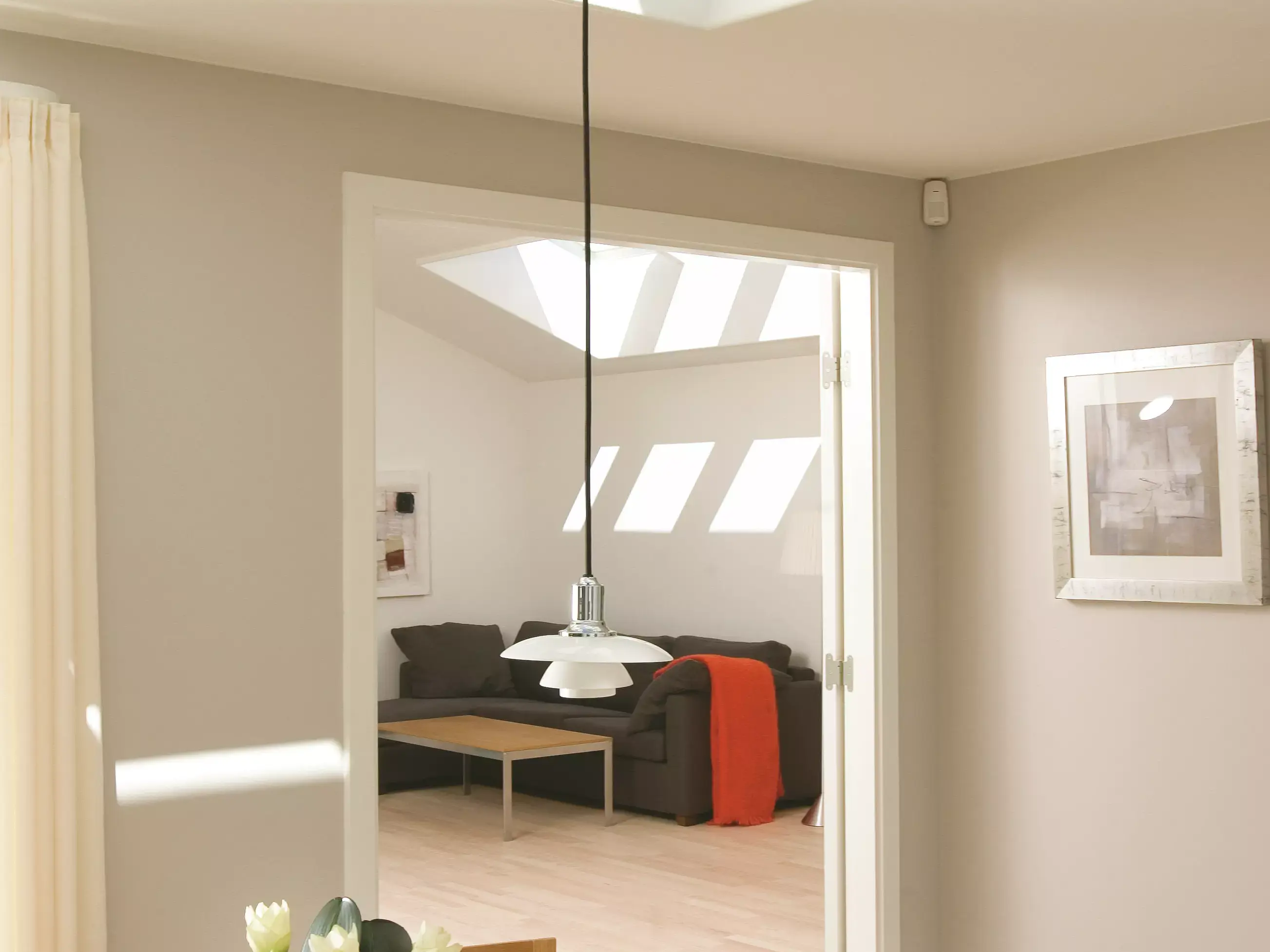 Salon confortable avec canapé et table basse, éclairé par une fenêtre de toit VELUX.