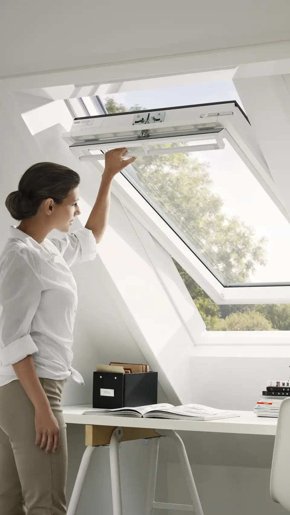 Frau öffnet ein VELUX Dachfenster in ihrem Büro