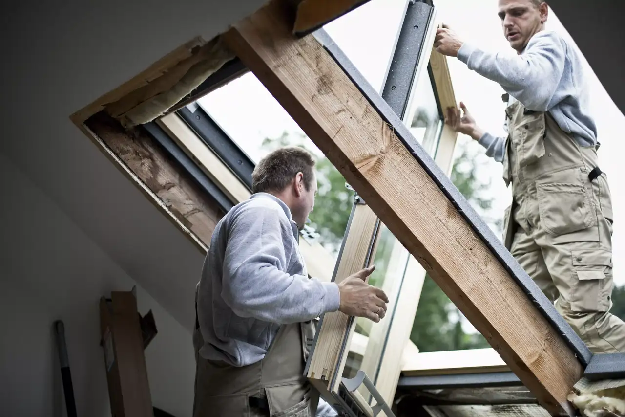 Dwóch instalatorów ostrożnie wymienia okno dachowe, aby zwiększyć ilość naturalnego światła na poddaszu | VELUX