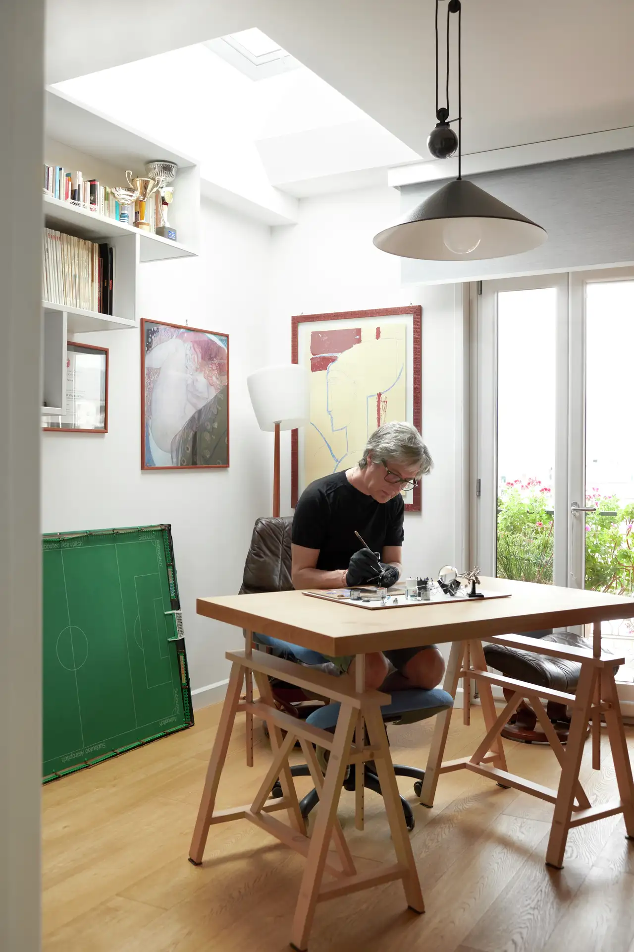 Un uomo dipinge delle figure nella sua stanza degli hobby con finestre per tetti piani | Rivista VELUX