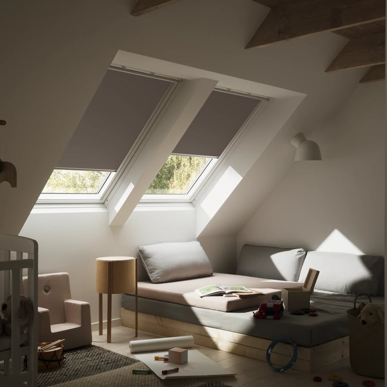 Attic kids room with sloped ceiling and VELUX roof windows, cozy decor.