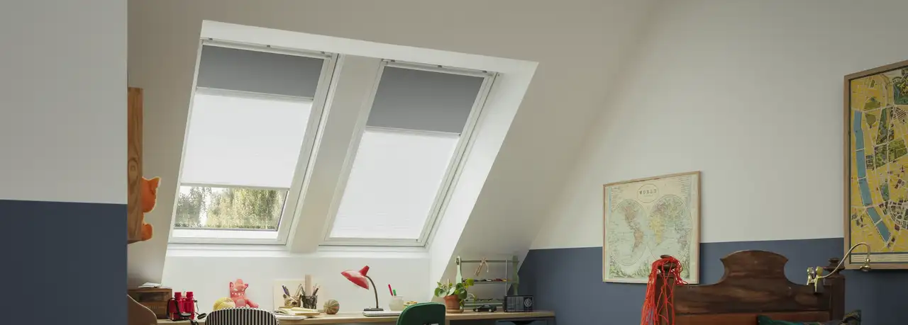 Attic kids room with sloped ceiling and VELUX roof windows, colorful decor.