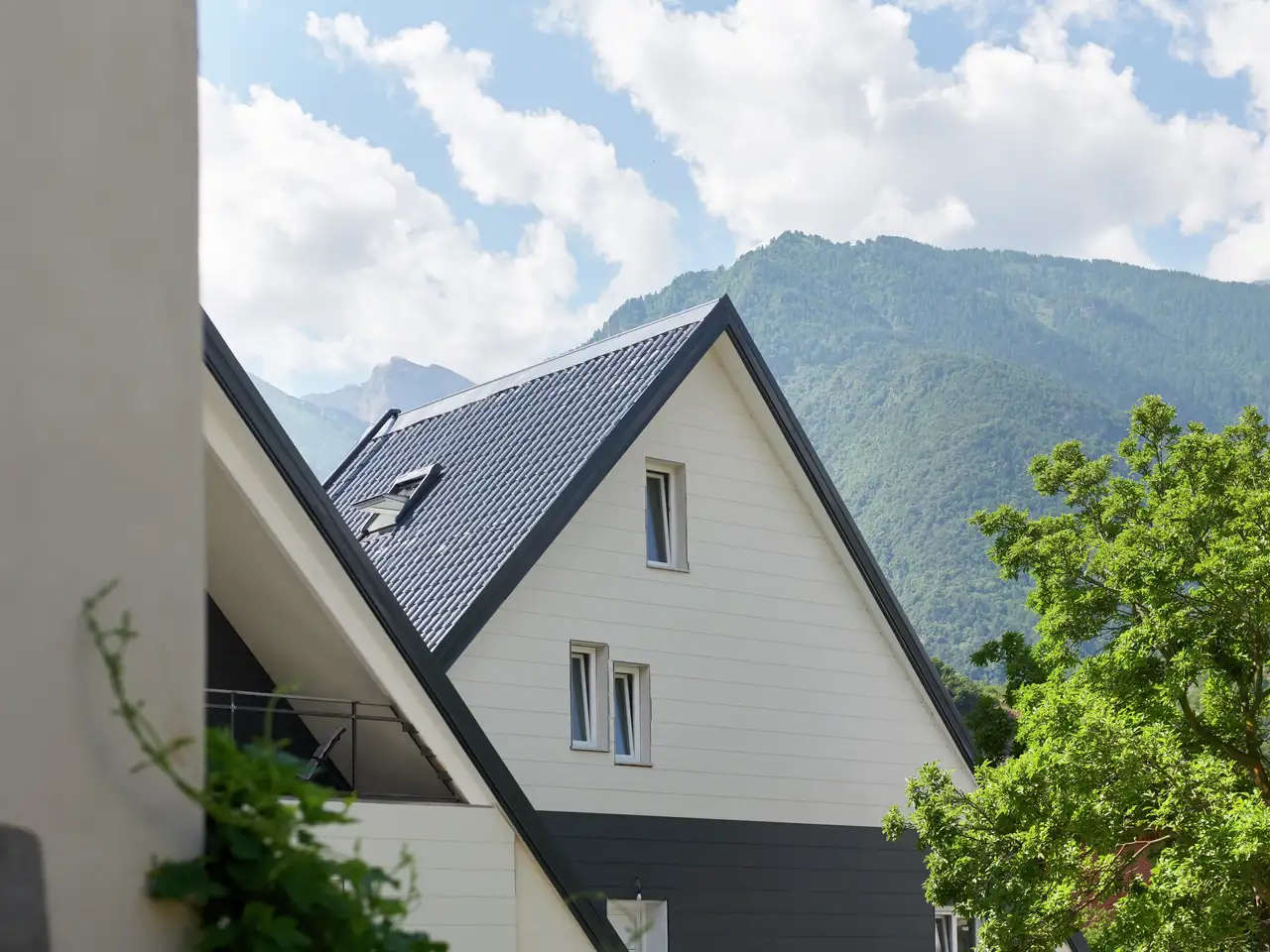 Casa moderna con tetto a falde ripide e finestra per tetti VELUX, vista sulle montagne.