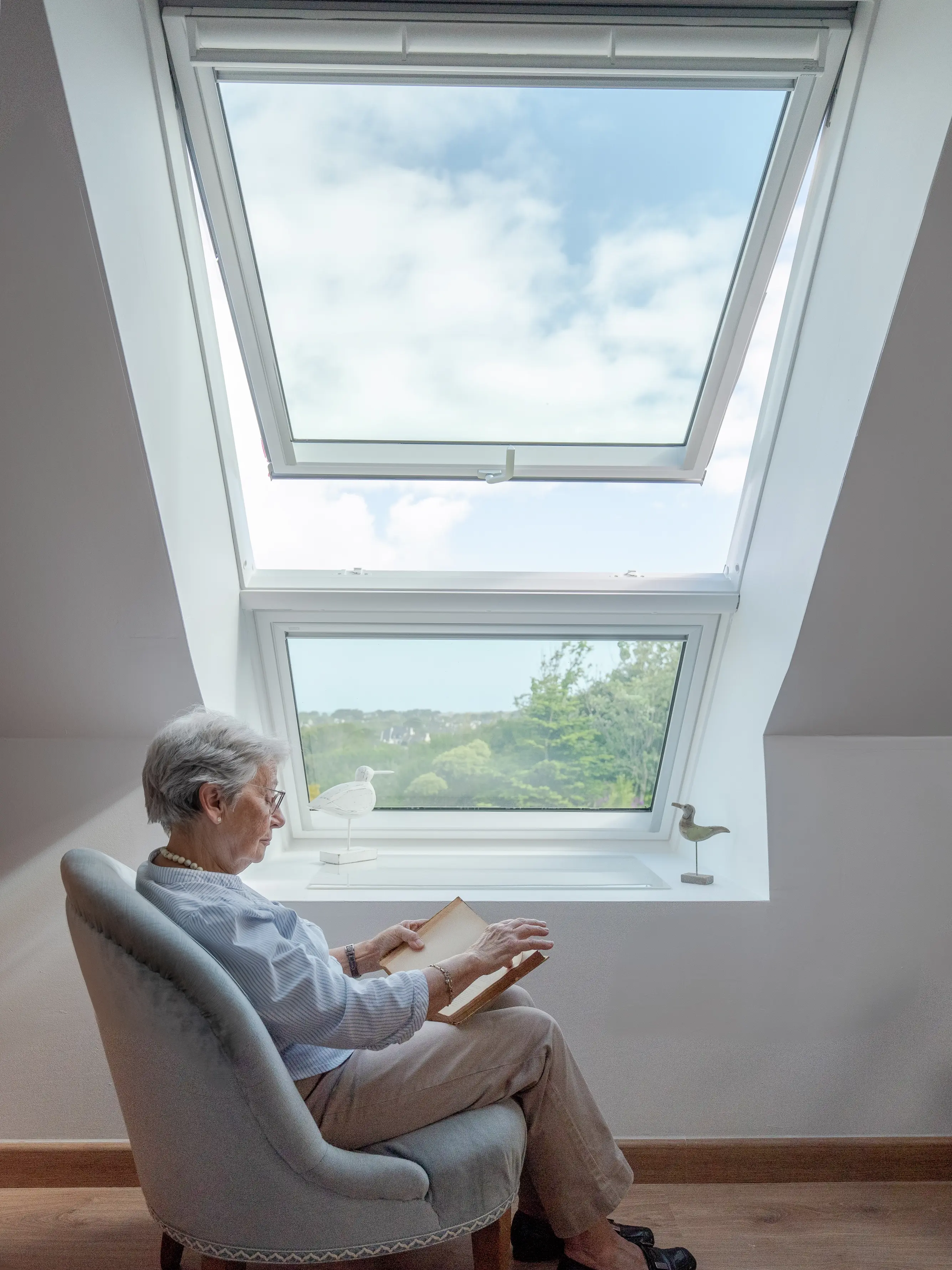 Coin lecture cosy dans le comble avec fenêtre de toit VELUX et lumière naturelle.