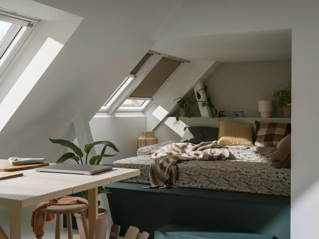 Zona letto in un open space con finestre per tetti e tende per modulare l’ingresso della luce.