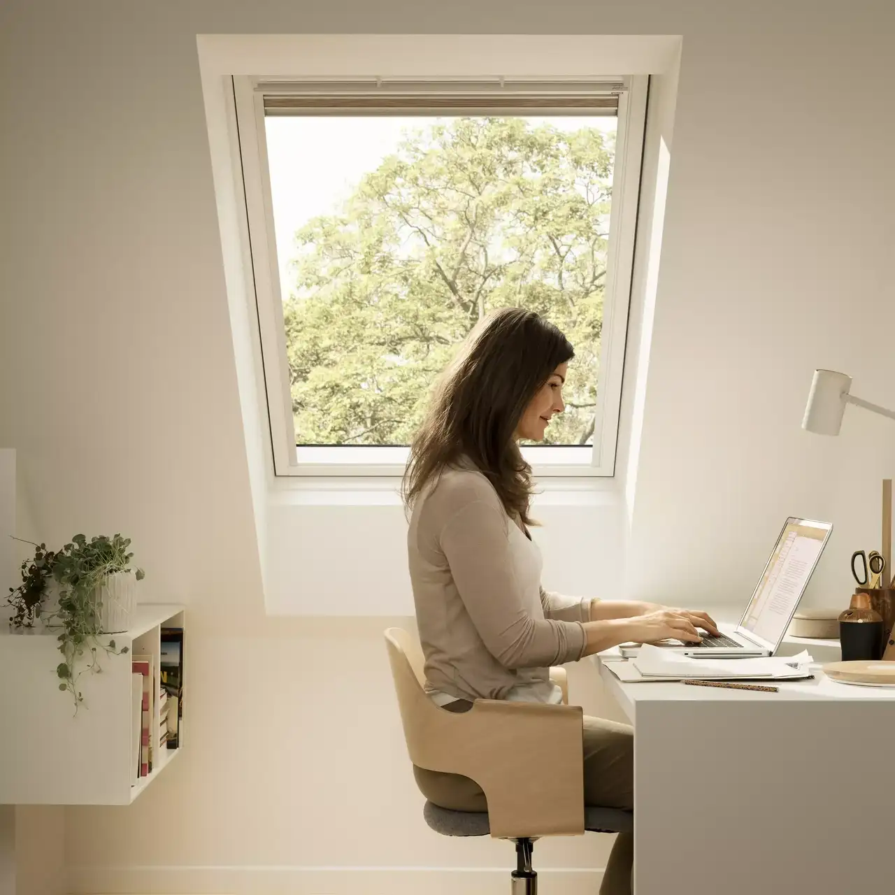 Homeoffice mit VELUX-Fenster, Schreibtisch, Laptop und Pflanzen, die einen ruhigen Arbeitsplatz bieten.