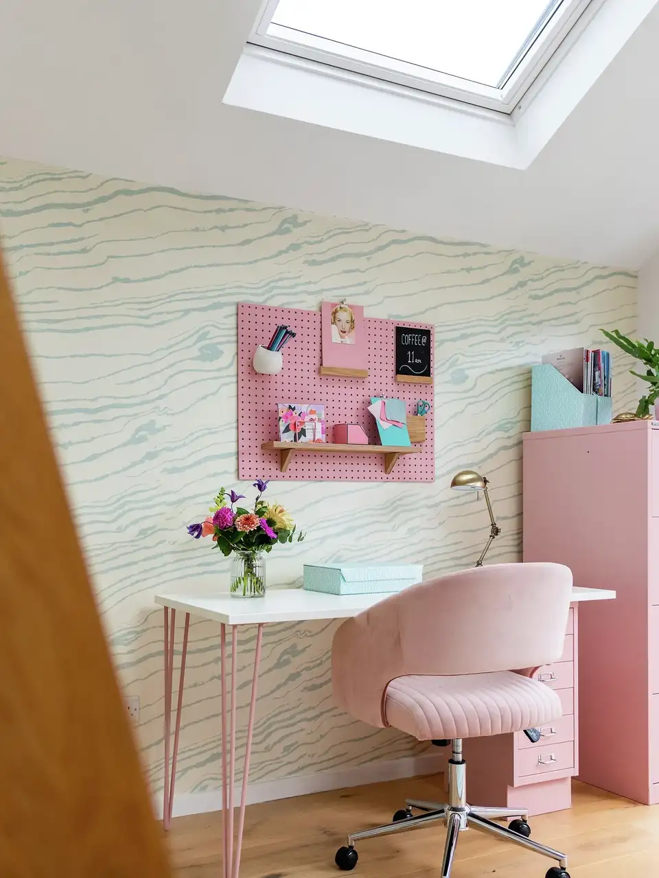Ufficio in mansarda con elementi decorativi rosa in uno spazio bianco e luminoso