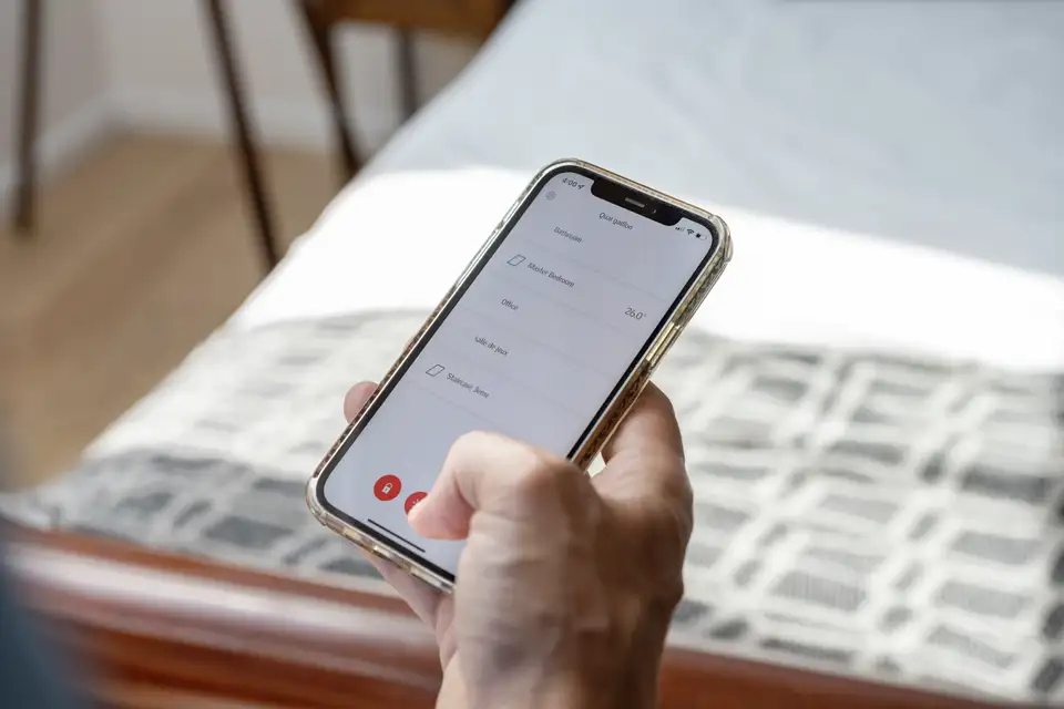 Un smartphone en cuya pantalla se muestra la app para controlar las persianas a distancia.