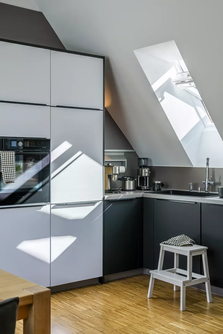 Moderne Küche mit schwarzen Schränken und einem VELUX Dachflächenfenster, das den Raum erhellt.