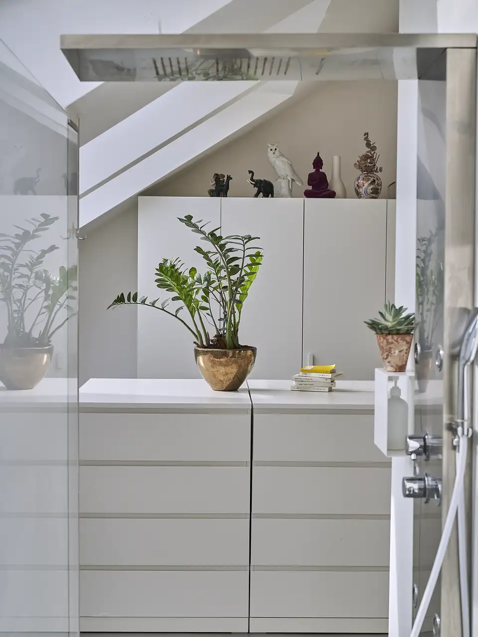 Cabina armadio in mansarda con finestre per tetti VELUX e armadi e mobili bianchi.