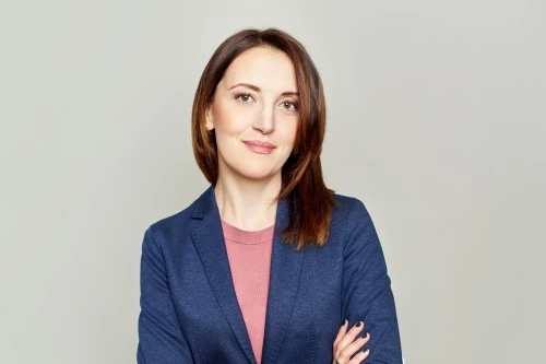 Confident woman in blue blazer with arms crossed against a light background
