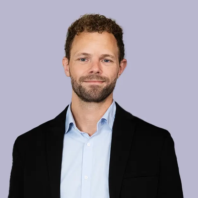 Person in a black blazer and light blue shirt, professional attire.
