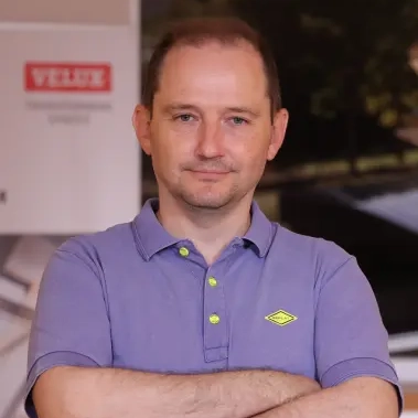 Man standing with folded arms in a bright showroom with VELUX displays in the background.