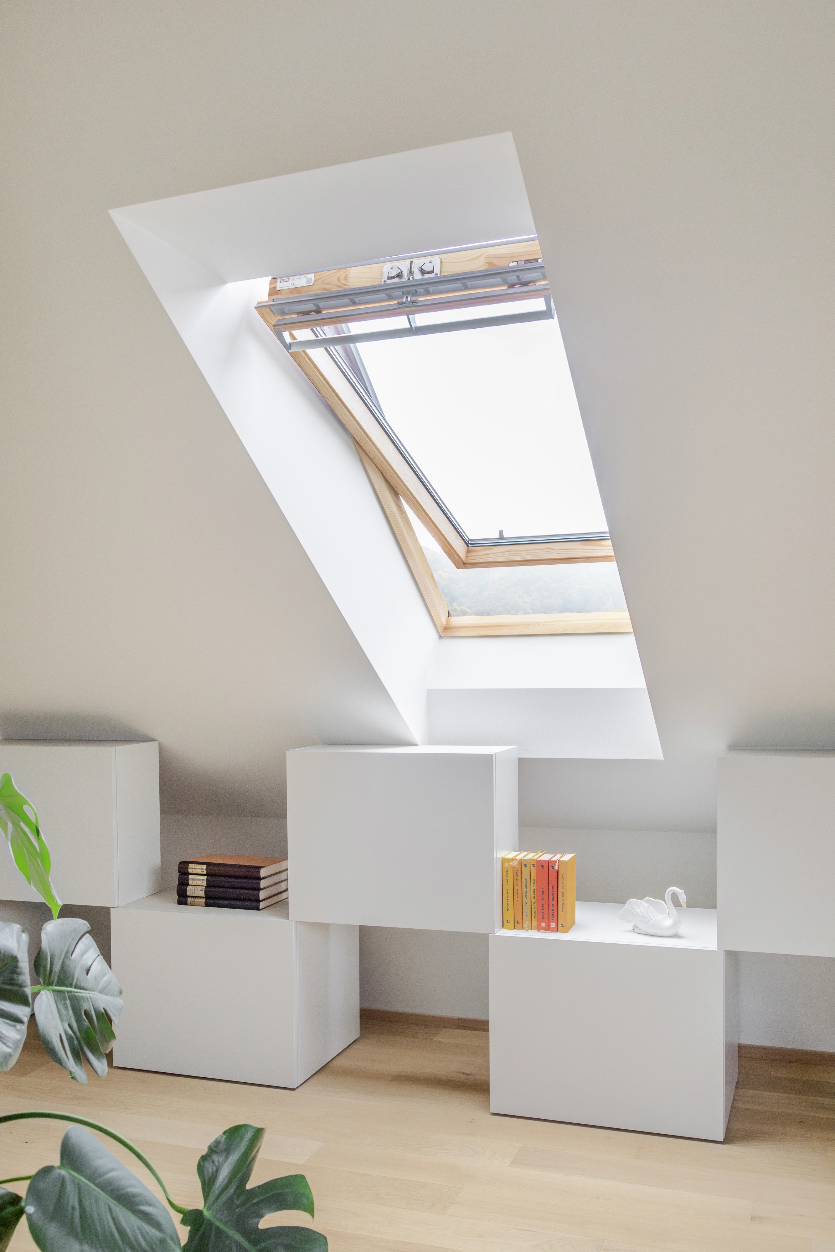 Svetlá podkrovná izba so šikmým stropom a otvoreným strešným oknom VELUX, minimalistický dekor