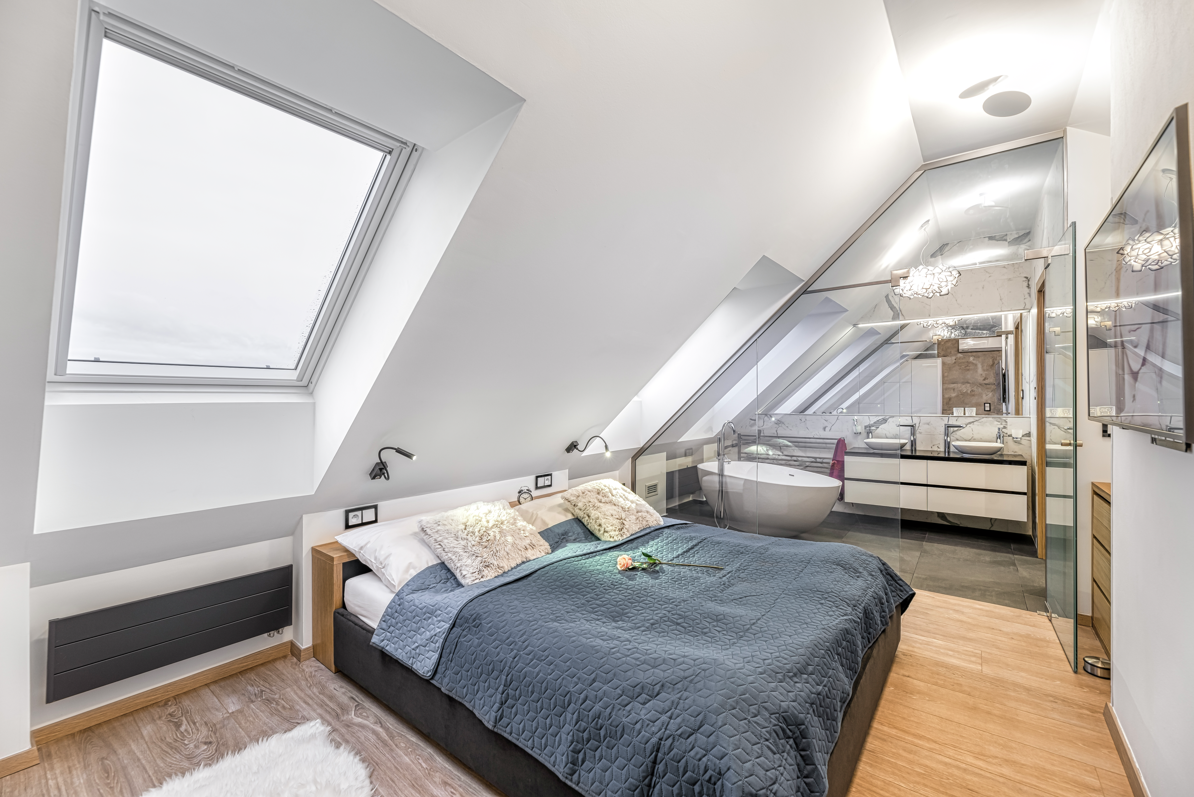 Attic bedroom with sloped ceiling, VELUX window, and modern bathroom.