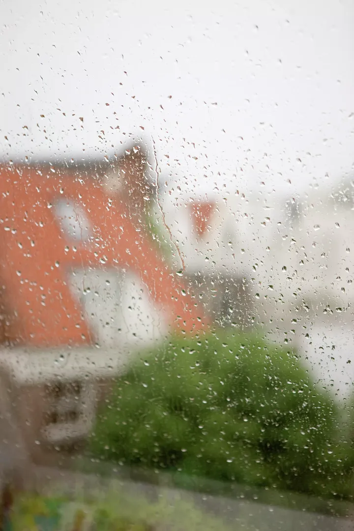 Nahaufnahme von Regentropfen auf einem VELUX Dachflächenfenster vor einem stürmischen Himmel.