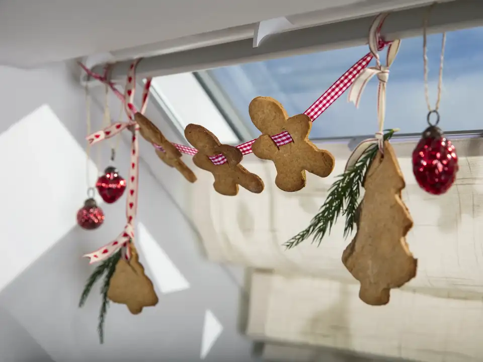 Festive ornaments hanging by a closed VELUX roof window in an attic room. 