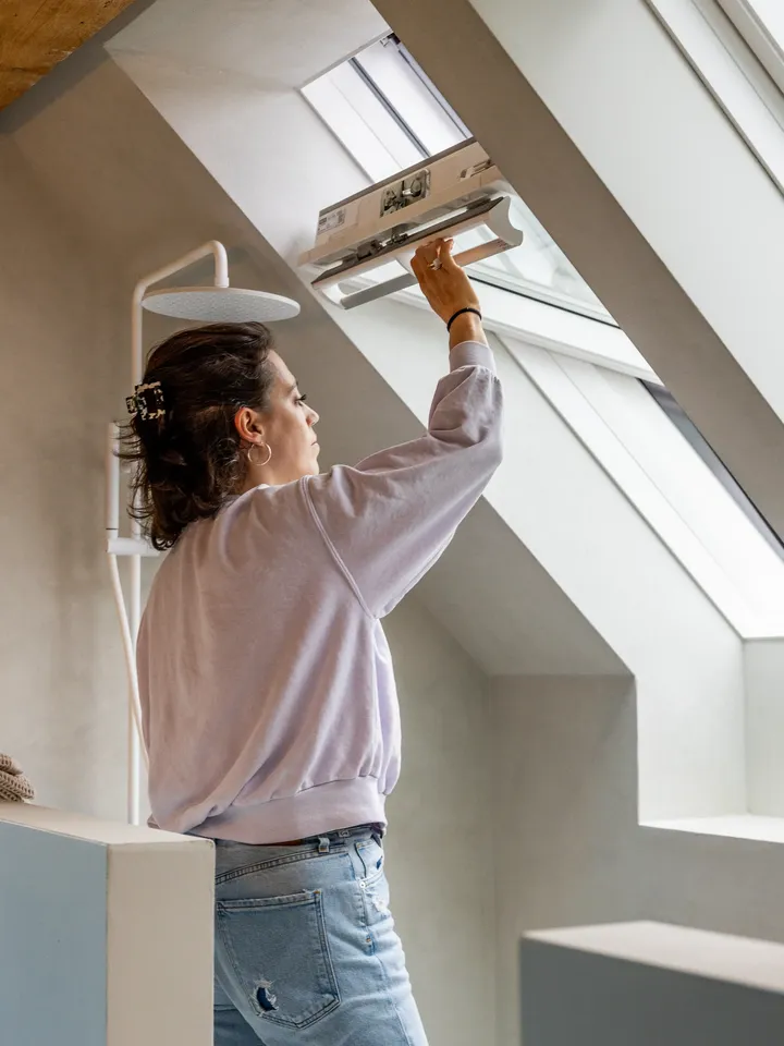 Жена отваря покривен прозорец с централна ос. | VELUX