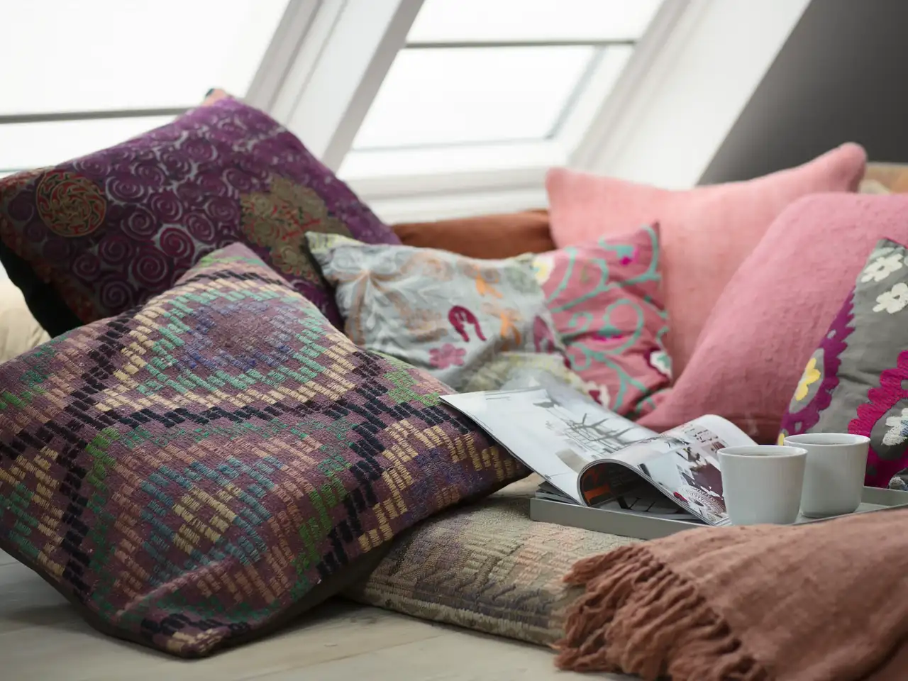 Kuschelecke im Boho-Stil mit bunten Kissen unter Dachfenstern | VELUX Magazin