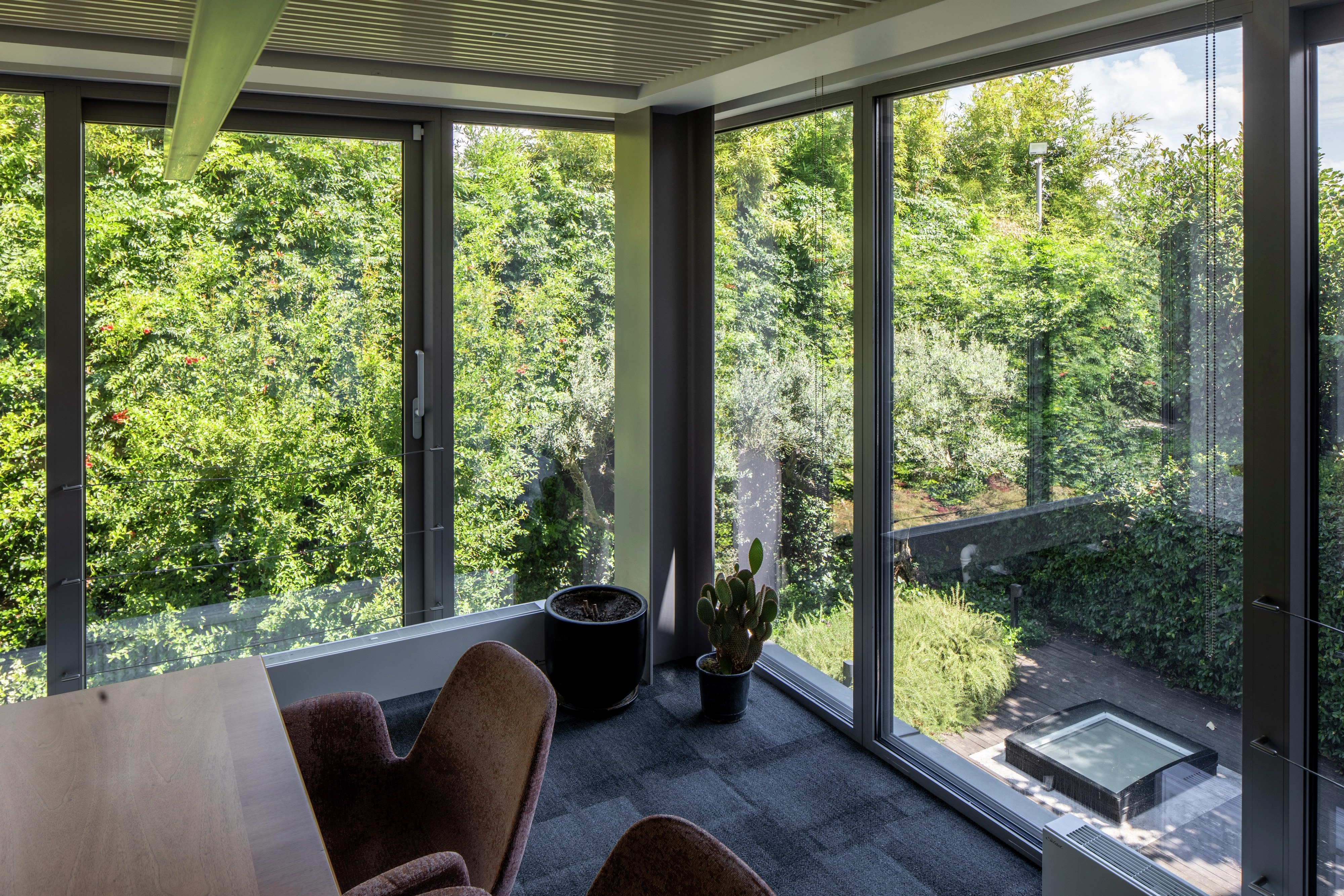 Office space with large windows overlooking a lush garden.