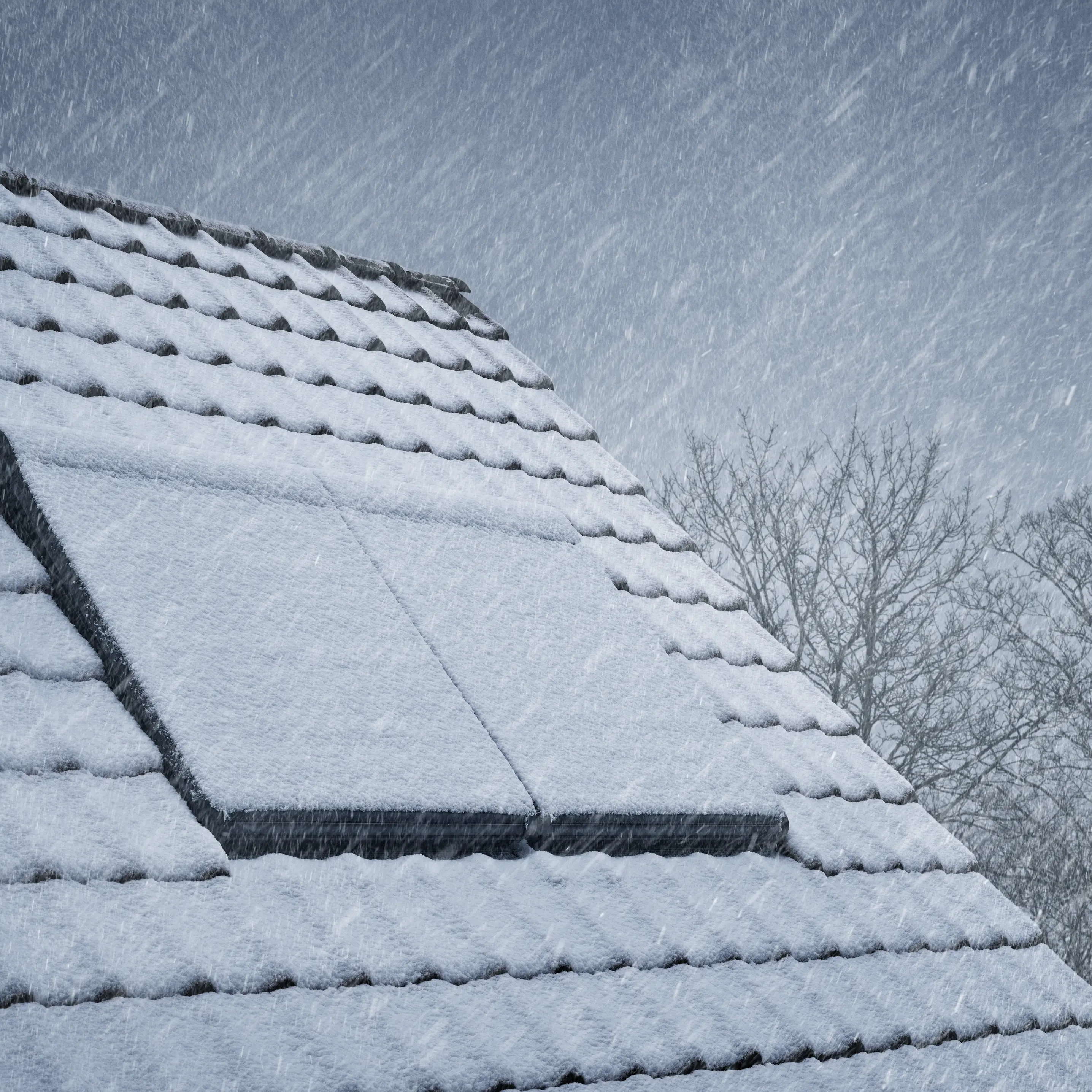 Snow-covered roof with closed VELUX window during heavy snowfall.