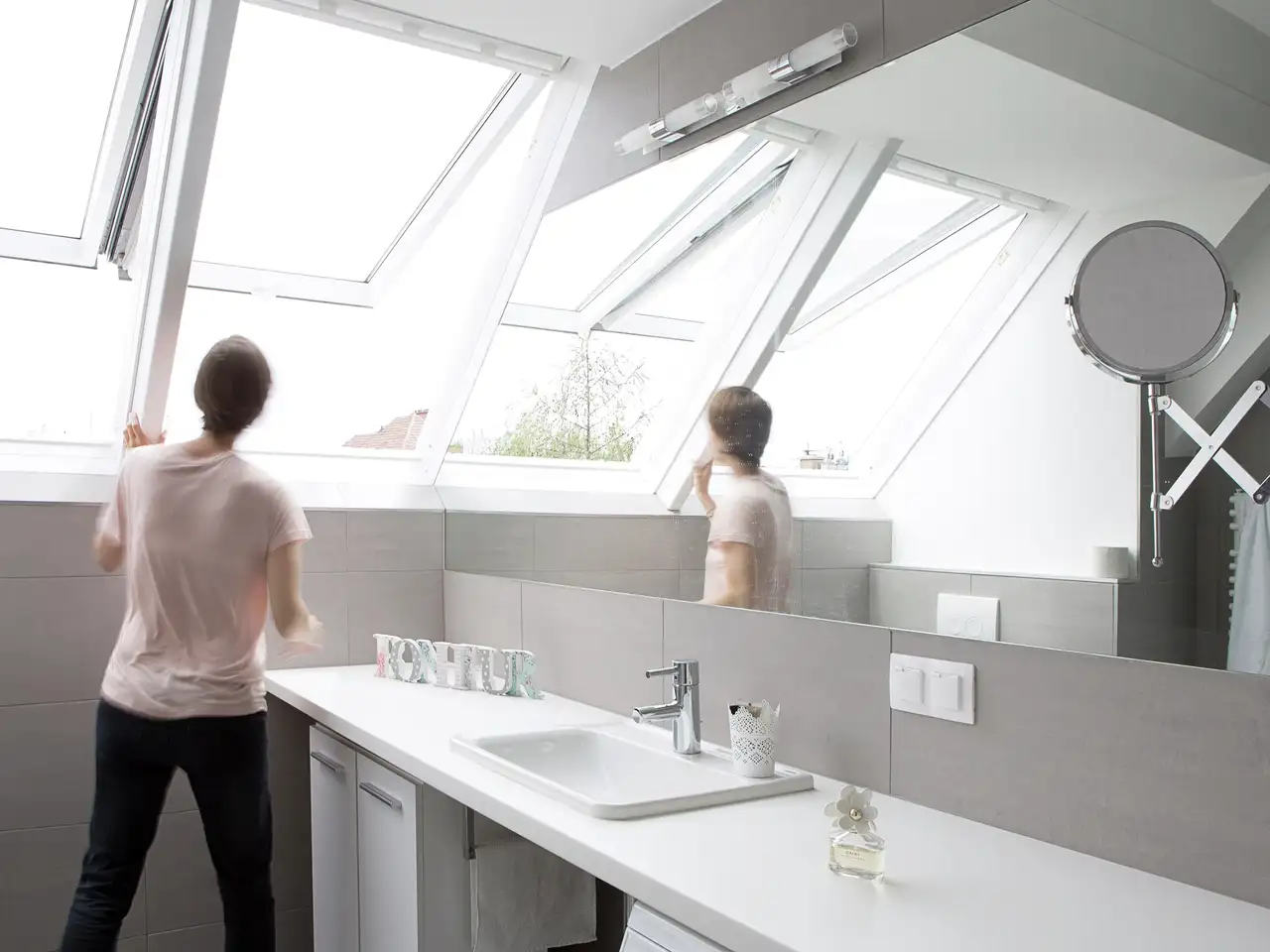 Frau steht an geöffneten Dachfenstern im Badezimmer | VELUX Magazin