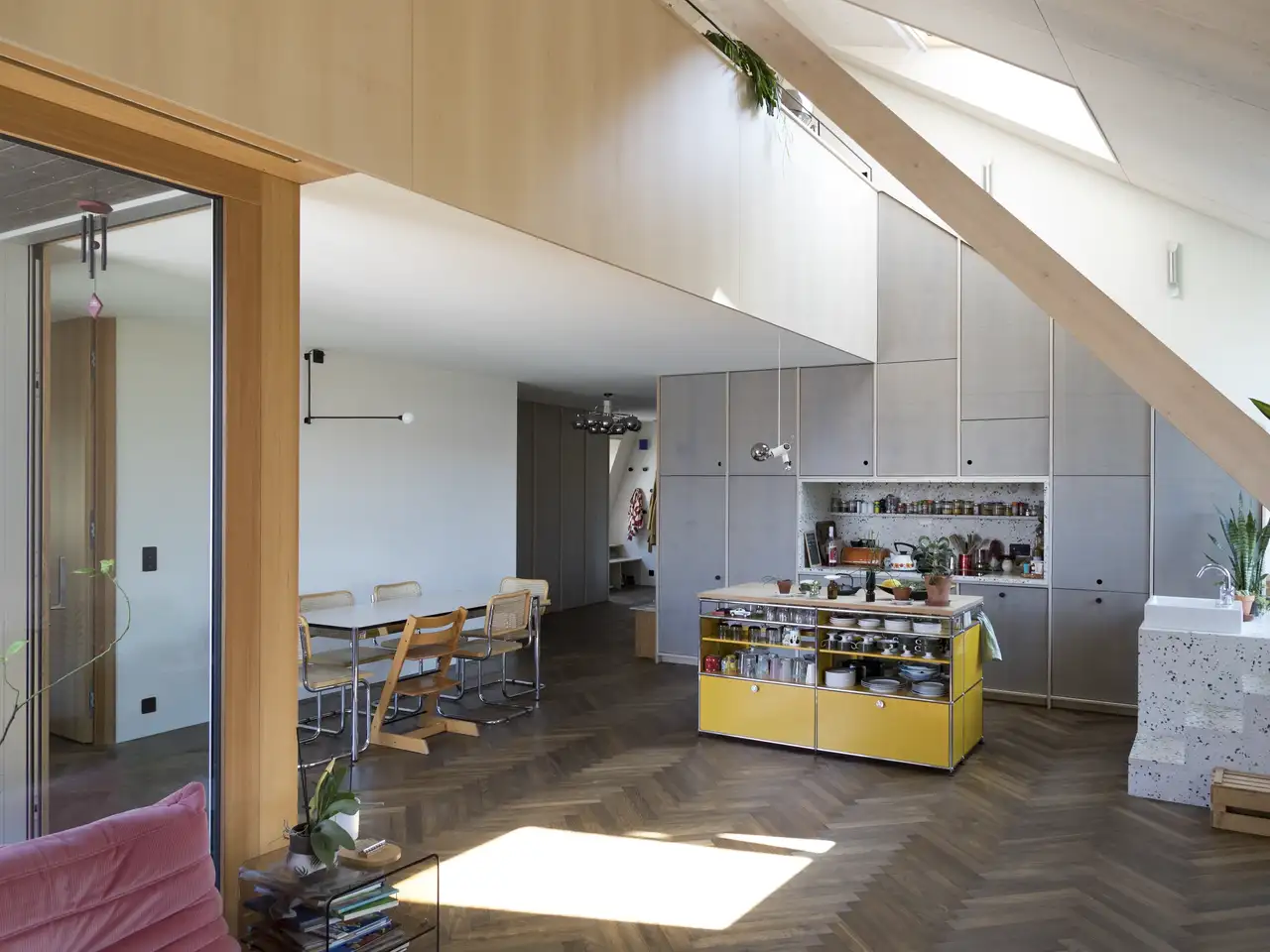 Cocina abierta al salón en espacio abuhardillado iluminada por una ventana de tejado