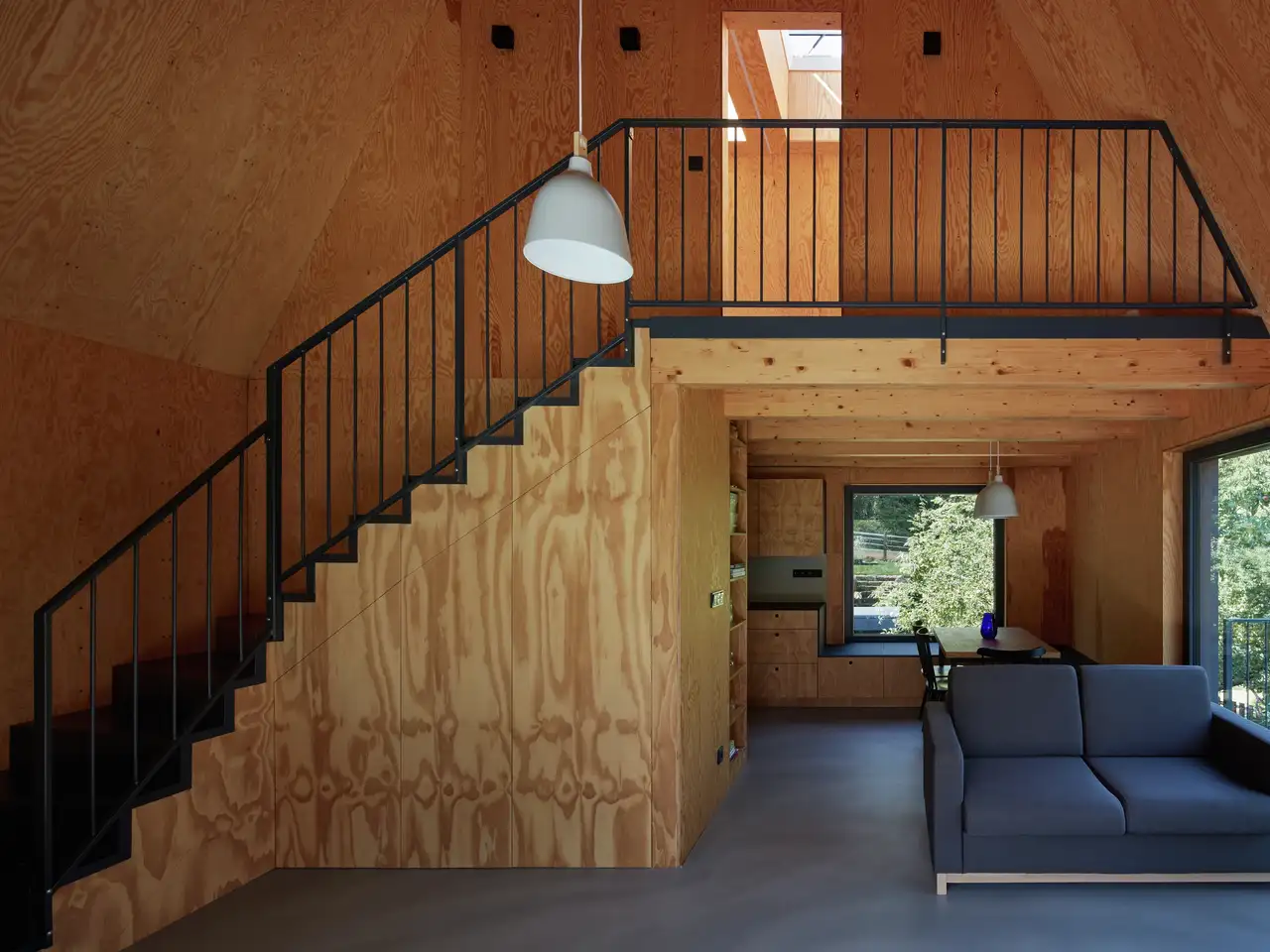Interni moderni in legno con soppalco, scala,  ampie finestre verticali e finestre per tetti VELUX.