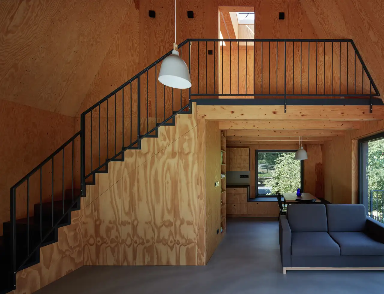  intérieur minimaliste en bois avec mezzanine, escalier, larges baies vitrées verticales et fenêtres de toit VELUX