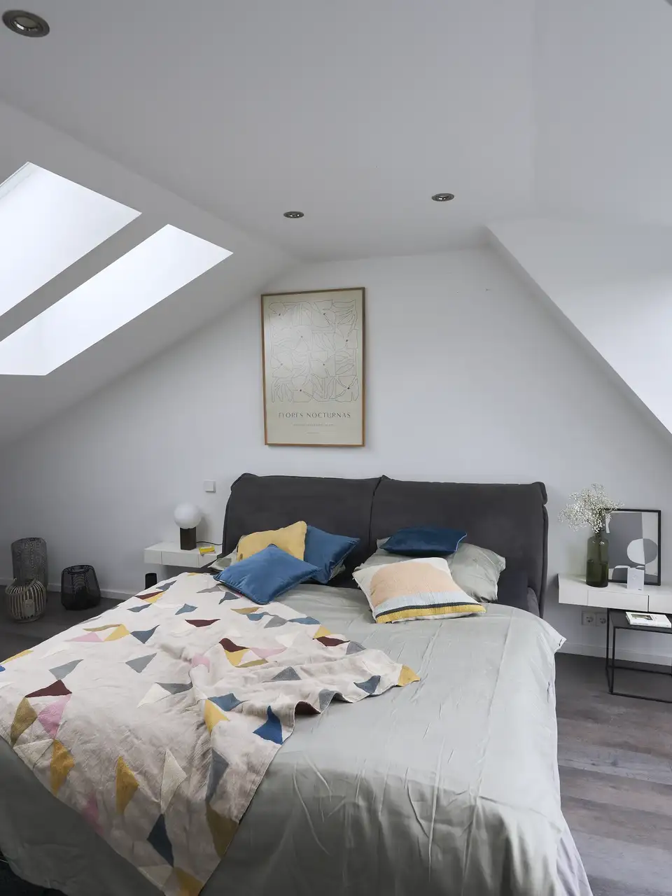 Camera da letto in mansarda con più finestre per tetti su pareti opposte