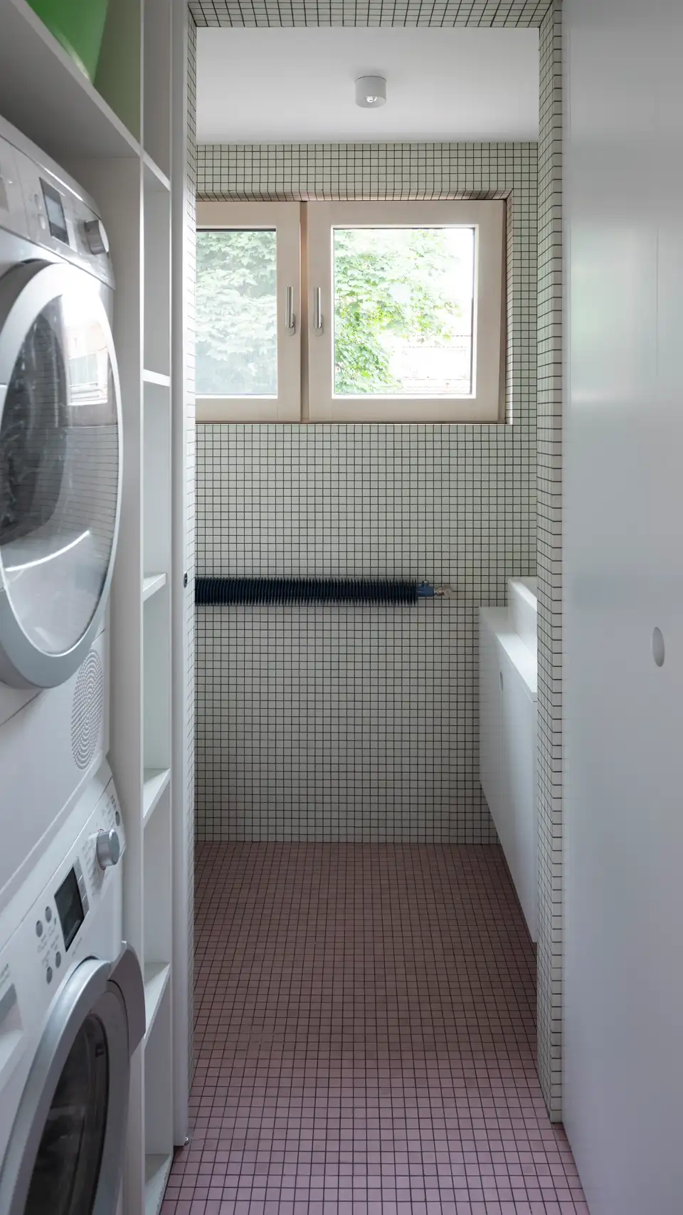 Bagno con angolo lavanderia con lavatrice e asciugatrice in colonna.