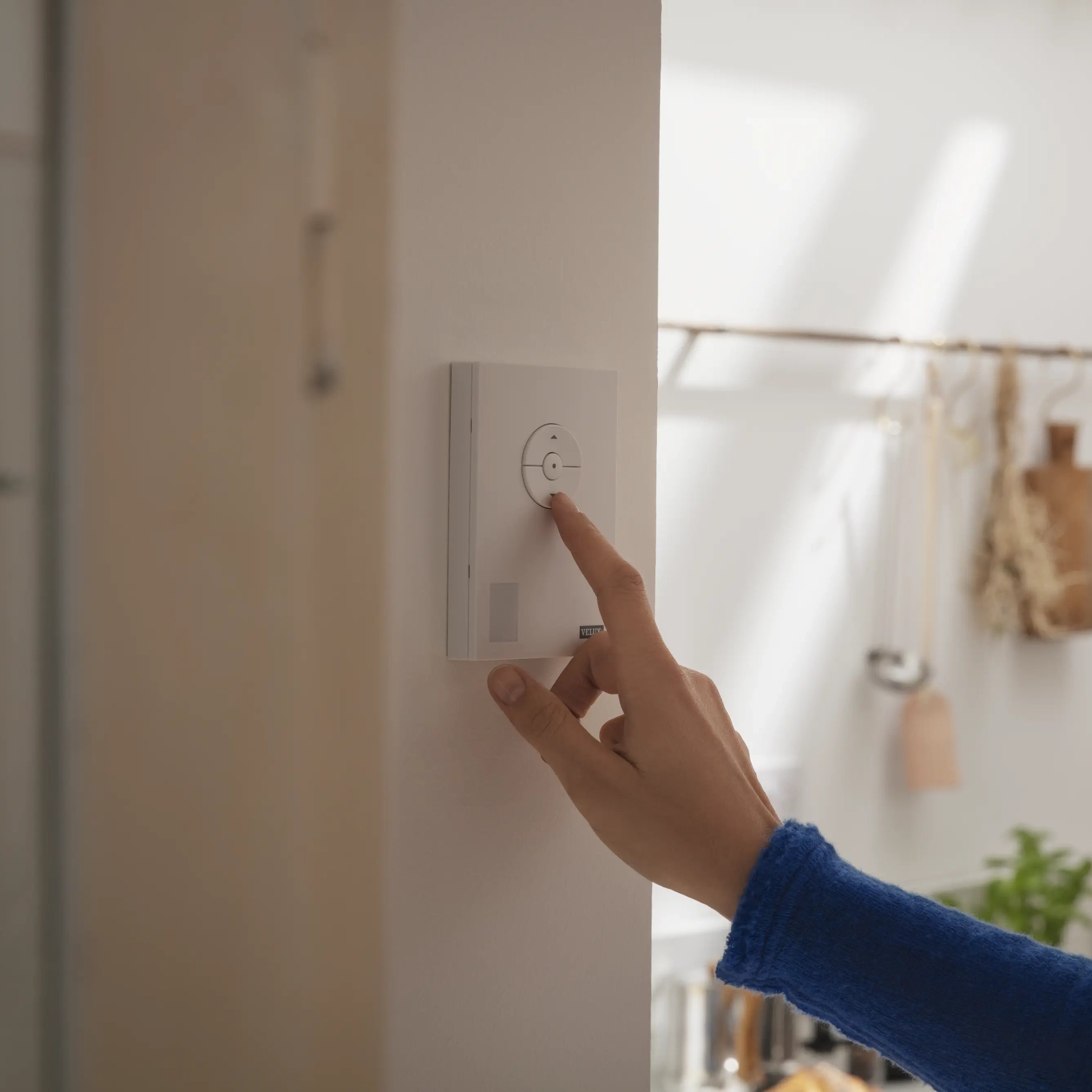 Person adjusting kitchen light settings with wall-mounted control panel.
