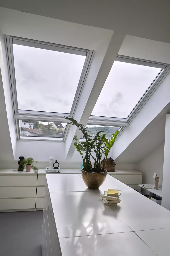 Moderne Dachbodenküche mit VELUX Dachflächenfenstern und geometrischen Wandmustern.